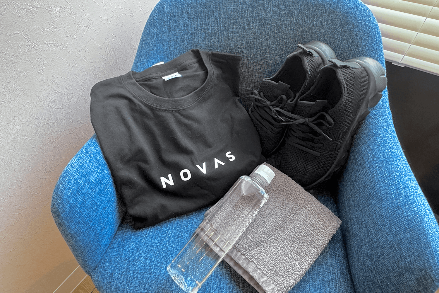 青い椅子の上にtシャツ、シューズ、タオル、水筒が乗っている画像