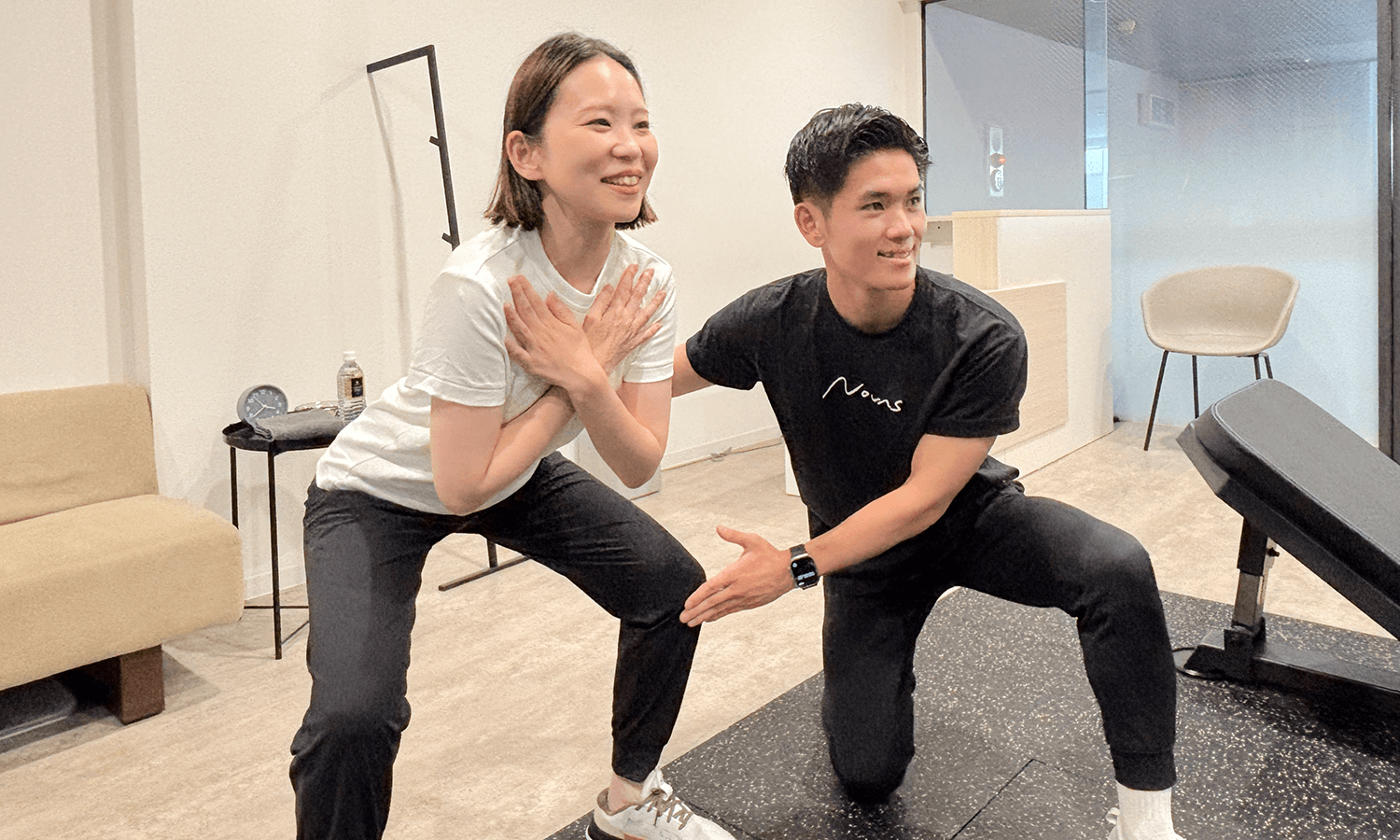 男性トレーナーが女性の方にスクワットのやり方を指導している画像