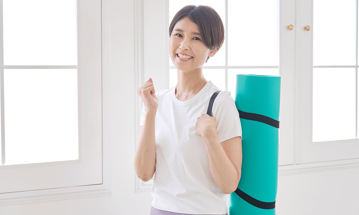 女性がストレッチマットを肩にかけてガッツポーズしている画像
